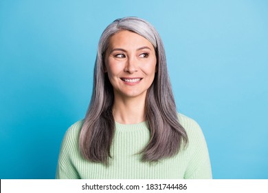 Portrait of beautiful smiling mature woman dressed green pullover isolated on blue color background