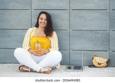 Portrait Of Beautiful And Smiling Stylish Plus Size Business Woman 30-35 Years Old In Yellow Fashion Clothes And Eyeglasses, Working Remotely On A Laptop On Vacation. 