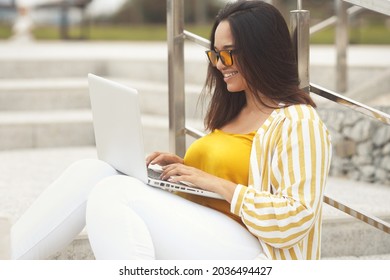 Portrait Of Beautiful And Smiling Stylish Plus Size Business Woman 30-35 Years Old In Yellow Fashion Clothes And Eyeglasses, Working Remotely On A Laptop On Vacation. 