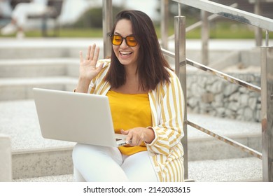 Portrait Of Beautiful And Smiling Stylish Plus Size Business Woman 30-35 Years Old In Yellow Fashion Clothes And Eyeglasses, Chatting And Say Hello On A Laptop On Vacation. 