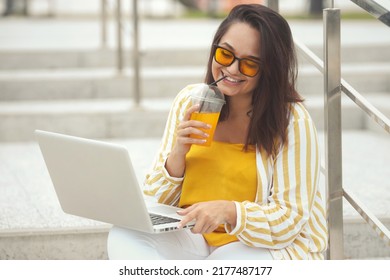 Portrait Of Beautiful And Smiling Stylish Plus Size Business Woman 30-35 Years Old In Yellow Fashion Clothes And Sunglasses, Working Remotely On A Laptop On Vacation