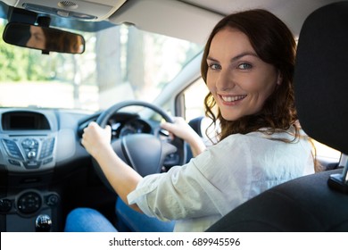 Portrait of beautiful smiling woman driving a car - Shutterstock ID 689945596