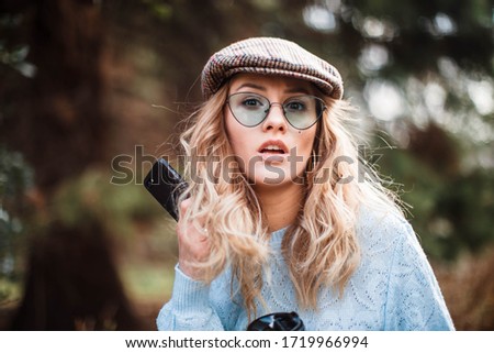 Similar – Blonde junge Frau mit Hut und Sonnenbrille, die bei Sonnenuntergang im Wald mit einem Mobiltelefon ein Foto macht.