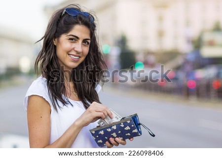Portrait of Beautiful Smiling Woman with Wallet in the Hands on the Street