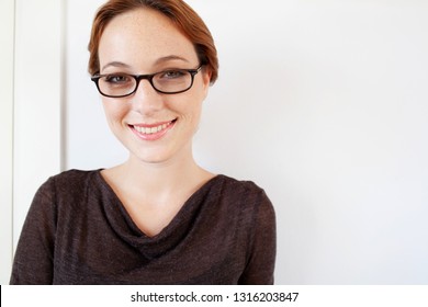 Portrait Of Beautiful Smiling Young Professional Woman Wearing Reading Glasses With White Wall Space, Smiling Personality Beauty, Lifestyle. Elegant Female Fun Expression With Spectacles, Quirky Face.