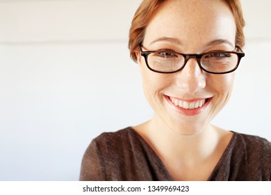 Portrait Of Beautiful Smiling Young Professional Woman Wearing Reading Glasses With White Wall Space, Smiling White Teeth, Beauty Lifestyle. Elegant Female Fun Expression With Spectacles, Quirky Face.