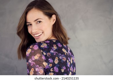 Portrait Of A Beautiful And Smiling Young Woman, Looking In Camera With Her Big Smile And White Teeth. Standing Isolated On Grey Concrete Background In A Nice Summer And Flower Dress. 