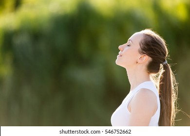 Portrait Of Beautiful Smiling Young Woman Enjoying Yoga, Relaxing, Feeling Alive, Breathing Fresh Air, Got Freedom From Work Or Relations, Calm And Dreaming With Closed Eyes, In Green Park, Copy Space