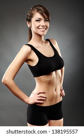 Portrait Of A Beautiful Sports Woman With Hands On Hips On Gray Background