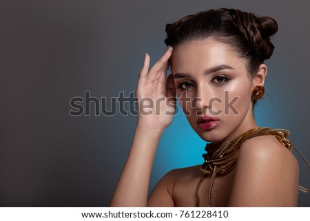 Portrait of a beautiful teenage girl in a fantasy image, on a blue background. With creative make-up and hairstyle
