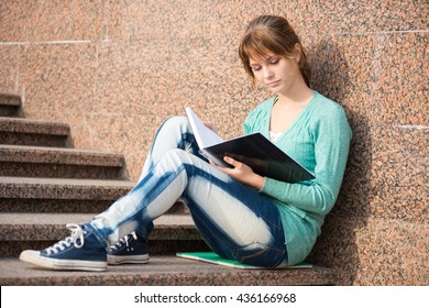 Portrait Of A Beautiful Teenage Student Girl Sitting On Stairs In Park With Copy Book And Studing. Sunny Summer Day. Modern And Casual Lifestyle. Woman With Note Pad.