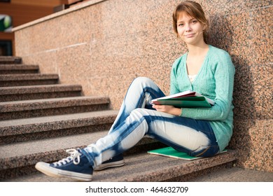 Portrait Of A Beautiful Teenage Student Girl Sitting On Stairs In Park With Copy Book And Studing. Sunny Summer Day. Modern And Casual Lifestyle. Woman With Note Pad.