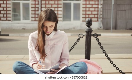 Portrait Of A Beautiful Teenage Student Girl Sitting With Copy Book And Studing. Sunny Summer Day. Modern  Casual Lifestyle. Woman  Note Pad.