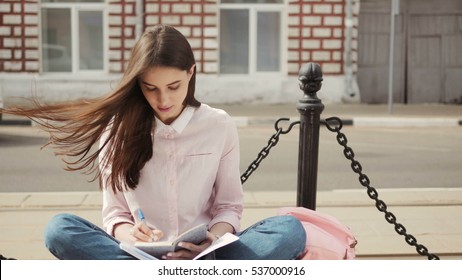 Portrait Of A Beautiful Teenage Student Girl Sitting With Copy Book And Studing. Sunny Summer Day. Modern  Casual Lifestyle. Woman  Note Pad.