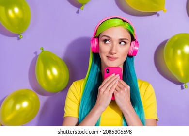 Portrait of beautiful trendy minded girl using device listening hit pop thinking balls flying isolated over violet purple color background