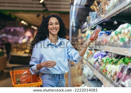 Portrait of beautiful vegetarian woman in supermarket, Latin American woman chooses vegetables for dinner, smiling and looking at camera.