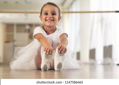 Portrait of a beautiful very young girl, in a dance school wearing a white tutu, she trains alone to learn new dance steps. Concept of: ambition, education, elegance and love for the dance...