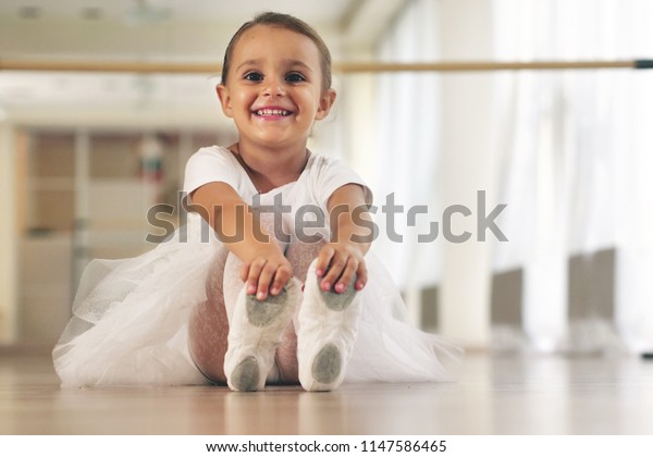 Portrait of a beautiful very young girl, in a\
dance school wearing a white tutu, she trains alone to learn new\
dance steps. Concept of: ambition, education, elegance and love for\
the dance...