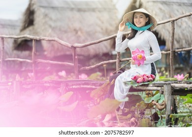 Portrait of beautiful vietnamese woman with traditional vietnam hat holding the pink lotus on the wooden bridge in big lotus lake, vietnam, aisan or southeast asia travel concept