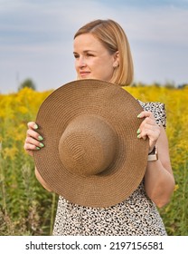 Portrait Of Beautiful White European Woman Looking Away And Holding Hat Outdoors.