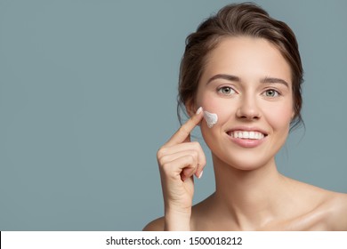 Portrait of beautiful woman applying cream on her face.