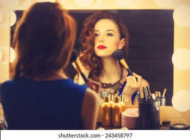Portrait of a beautiful woman as applying makeup near a mirror. Photo in retro color style. - Shutterstock ID 243458797