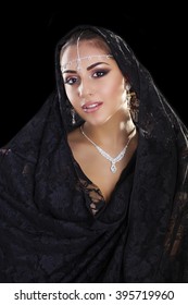 Portrait of a beautiful woman with arabian makeup in black paranja isolated on dark background