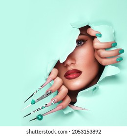 Portrait Of A Beautiful Woman With Art Make Up In Glamorous Style, Creative Long Nails On A Blue Background . Design Manicure. Beauty Face.