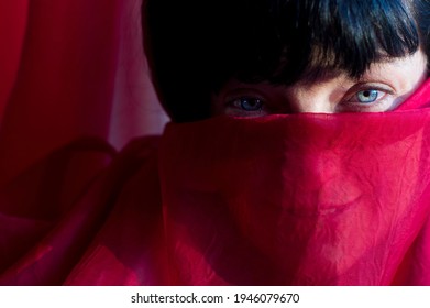 Portrait Of Beautiful Woman Behind A Red Curtain