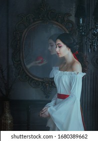 Portrait beautiful woman concept sleeping beauty fairytale Snow White. medieval clothes dress. Gothic princess makeup red lips. Ghost female hand with poison apple is reflected vintage antique mirror