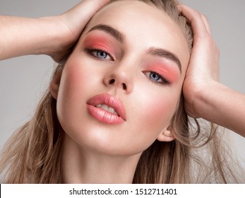 Portrait of a beautiful woman with a coral color makeup. Attractive blonde  girl with  bright fashion make-up, posing at studio. Beautiful female face. Closeup portrait of pretty lady. Fashion model.
