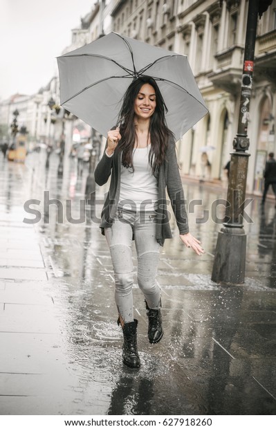 雨の中で傘を差して踊る美しい女性のポートレート 水たまりにはねる の写真素材 今すぐ編集