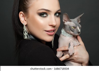 Portrait Of Beautiful Woman In Diamond Earrings With Cat On Black Background