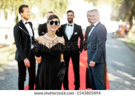 Portrait of a beautiful woman dressed in retro style as a famous movie actress on the red carpet during awards ceremony outdoors