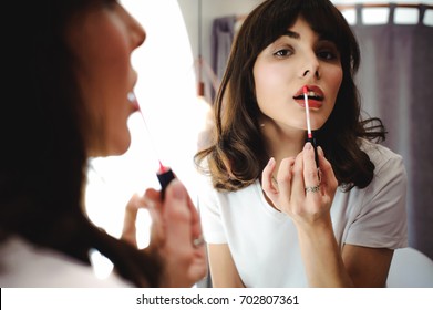 Portrait Of A Beautiful Woman, Dyes Her Lips Lipstick Pink, Looking In The Mirror