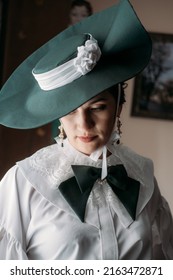 Portrait of beautiful woman in green vintage hat veil 1800s early 1900s clothing.