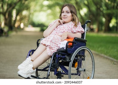 Portrait of beautiful woman with hairstyle looking at camera while sitting in wheelchair among green summer park. Lifestyles of people with chronic health disease. - Shutterstock ID 2092446037