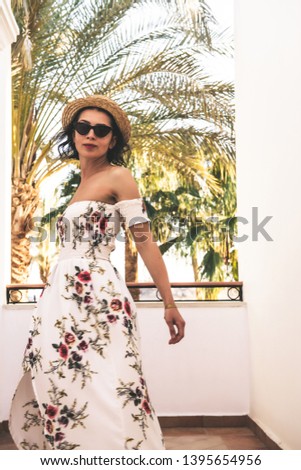 portrait of beautiful woman in hat and long dress near tropical beach 