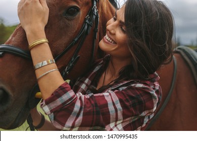 Portrait of beautiful woman and horse at the horse farm. Cowgirl petting her horse and smiling. - Powered by Shutterstock