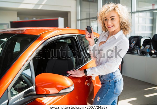 Portrait of beautiful woman with key in hands near
her new car
