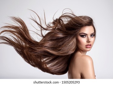 Portrait of a beautiful woman with a long hair. Young  brunette model with  beautiful hair - isolated on white background. Young girl with hair flying in the wind.
