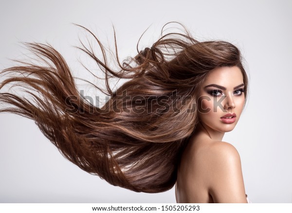 長い髪の美しい女性のポートレート 白い背景に若いブルネットモデルと美しい髪 髪が風になびく若い女の子 の写真素材 今すぐ編集