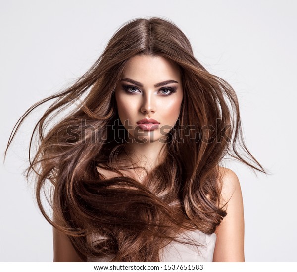 Portrait of a beautiful woman with a
long hair. Young  brunette model with  beautiful hair - isolated on
white background. Young girl with hair flying in the
wind.