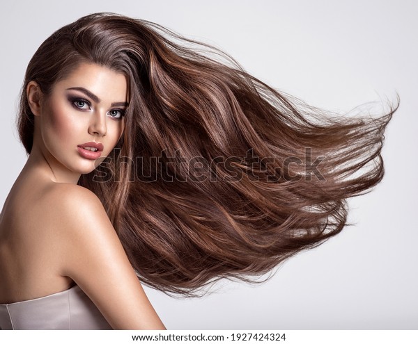 Portrait of a beautiful woman with a\
long hair. Young  brunette model with  beautiful hair - isolated on\
white background. Young girl with hair flying in the\
wind.
