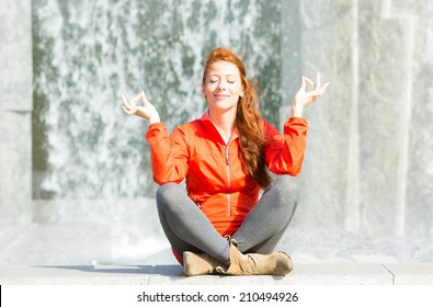 Portrait Beautiful Woman Meditating Yoga In Lotus Position Isolated Outdoors Park Waterfall Background. Urban Life Style, Stress Relief Techniques. Positive Facial Expression, Emotion, Life Perception