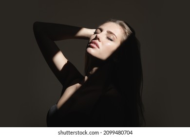 Portrait Of Beautiful Woman Model Looking Seductive And Sensual. Sensual Girl With Art Shadow Light. Beauty Face With Dramatic Studio Light Isolated On Black.