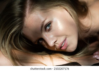 Portrait Of Beautiful Woman Model Looking Seductive And Sensual. Blonde Smiling Girl Closeup Face. Beauty Face With Dramatic Studio Light Isolated On Black.