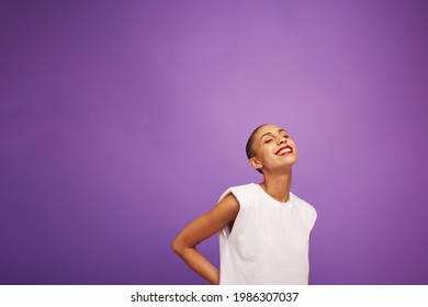 Portrait of a beautiful woman model standing on purple background. Female model in casual outfit and makeup smiling with eyes closed. - Powered by Shutterstock