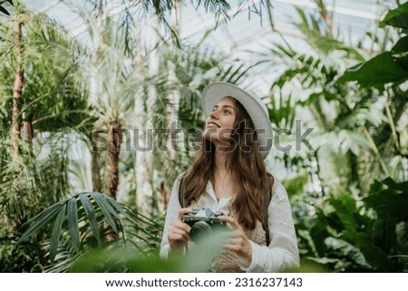 Portrait of beautiful woman photographer in botanical garden.