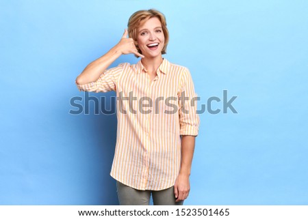 Portrait of beautiful woman pretending that talking on smart phone, always in conncetion, close up portrait, call me any time. isolated blue background